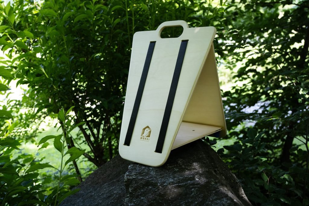 View of a MÖKKI bird feeder by Ulap design made of birch wood and black straps.